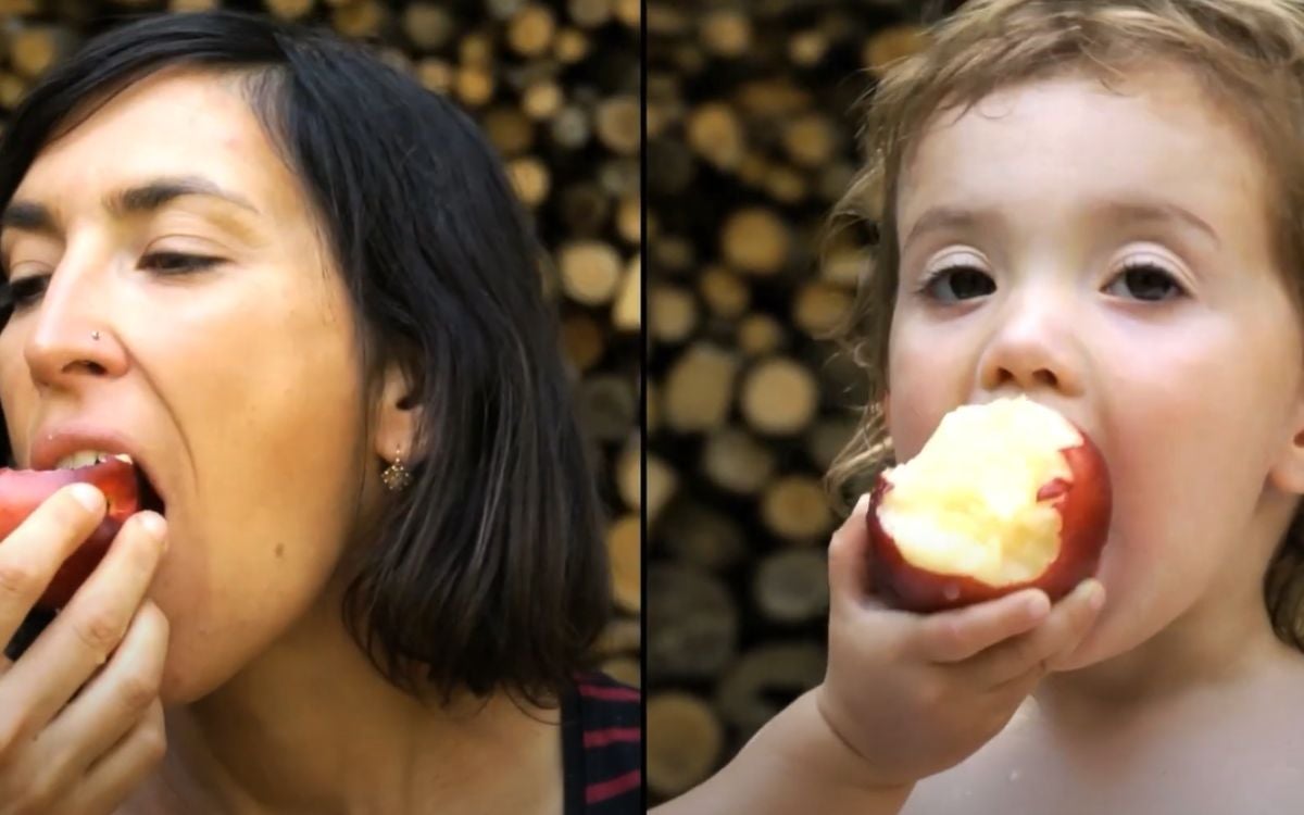 Mother and toddler eating an apple the same way