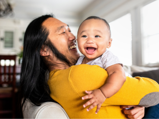 Asian dad holding young laughing baby