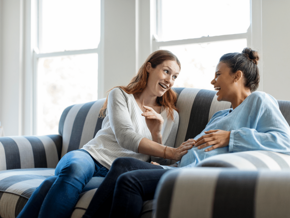 two women laughing one is pregnant