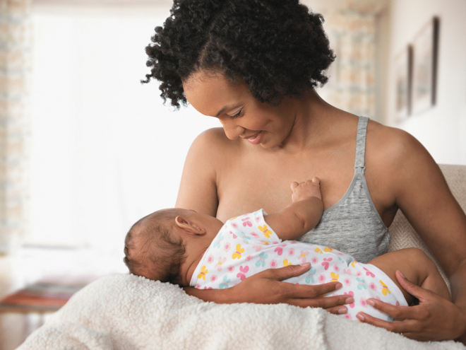 Mother breastfeeding her baby while smiling