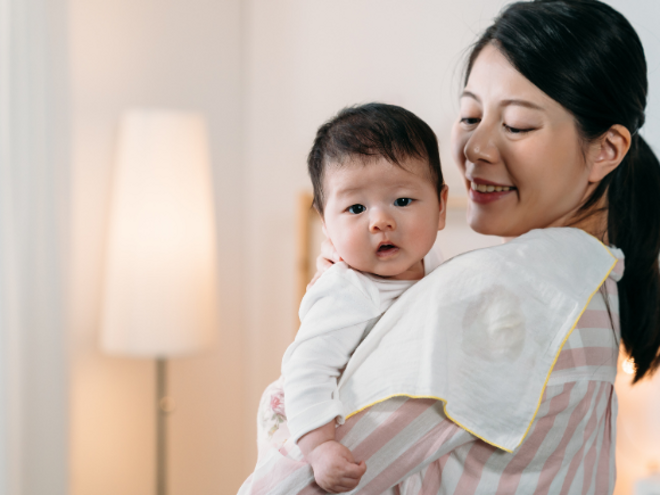 mother holding her baby with towel on her shoulder