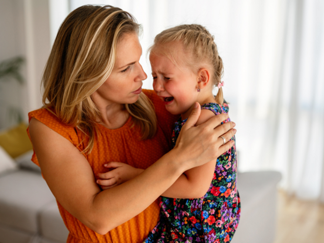 Woman holding her crying daughter