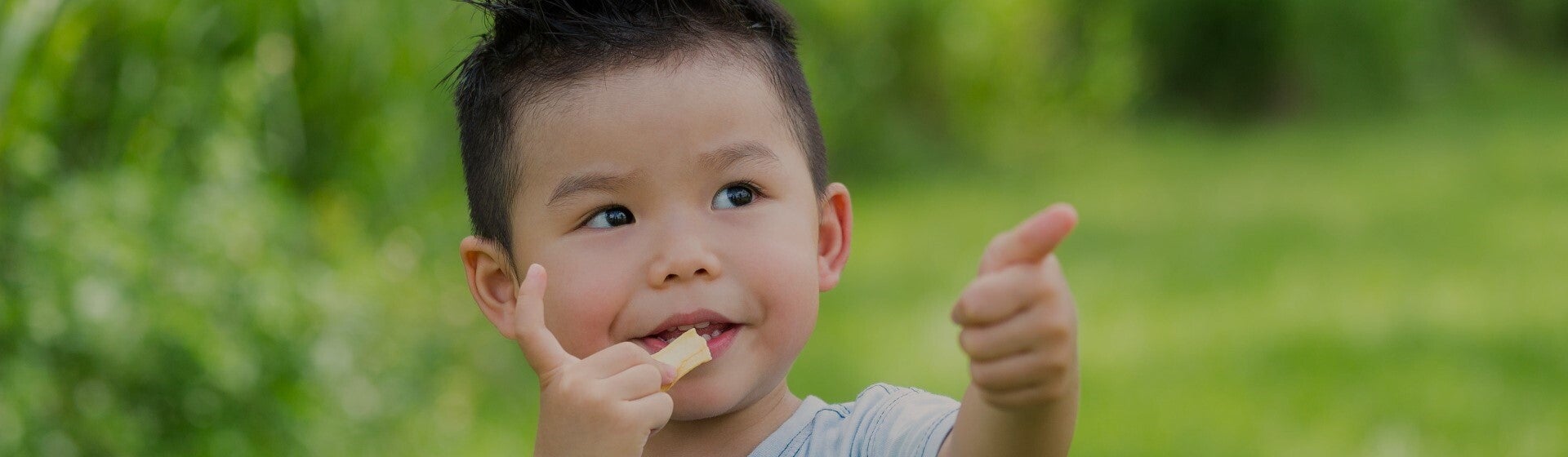 toddler eating a snack and giving thumbs up