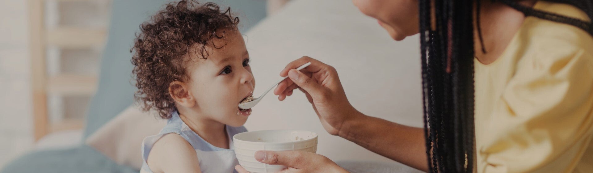 mother feeding child with spoon