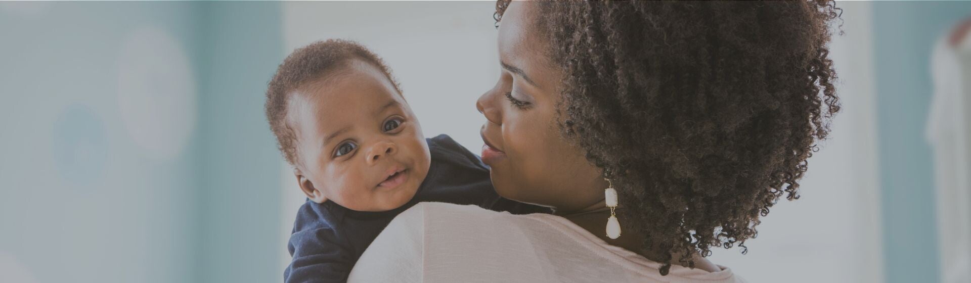 Woman in white tshirt with her baby looking over her shoulder