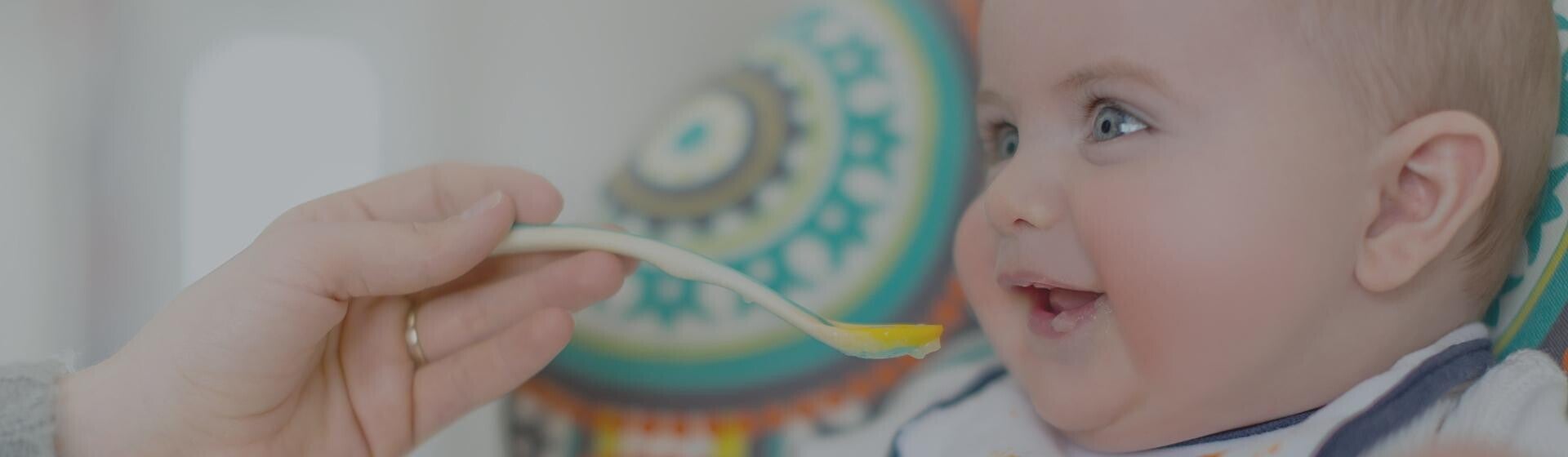 Baby eating infant cereal off a baby spoon