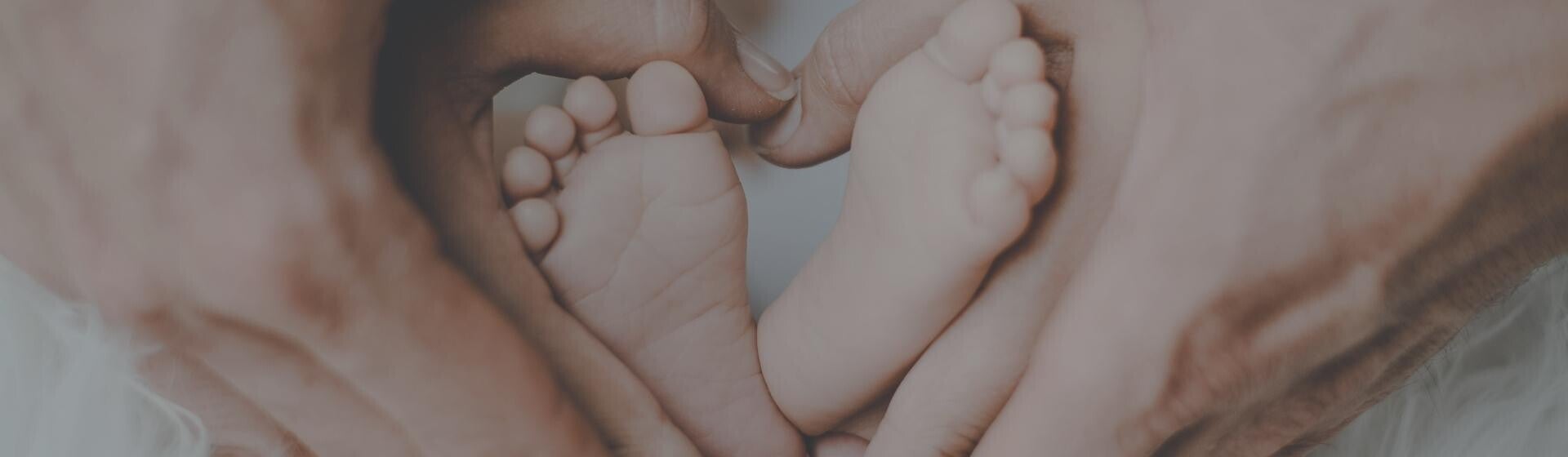 Parents cupping baby's foot in a love heart shape