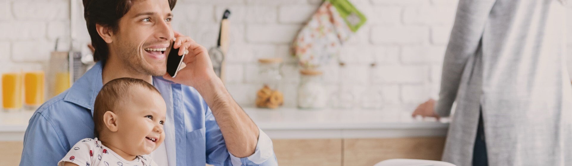 father talking on phone holding baby