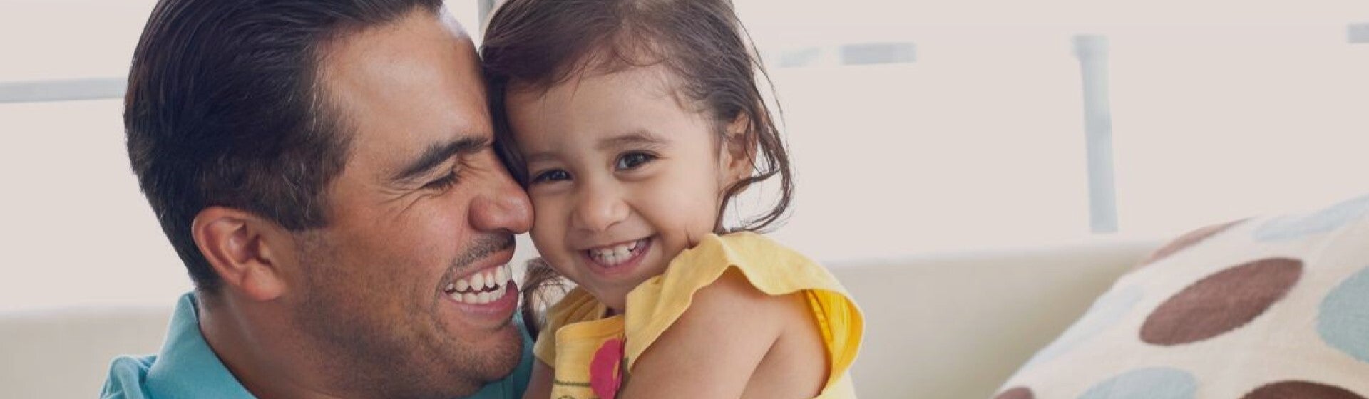 father smiling and tightly hugging child