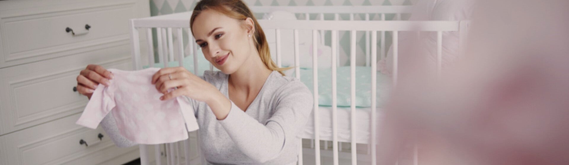 pregnant woman looking at newborn clothes