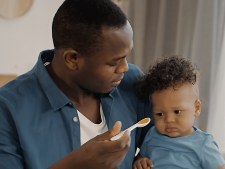 Dad feeding baby pureed food on a spoon