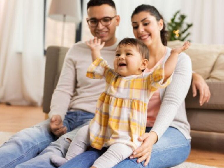 happy toddler in yellow flannel shirt sitting on parents lap