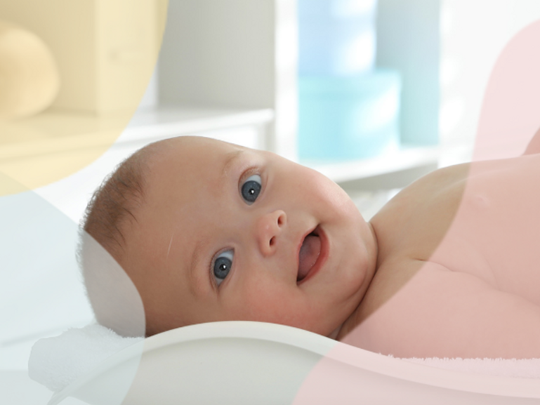 smiling baby lying on scale with nappy on